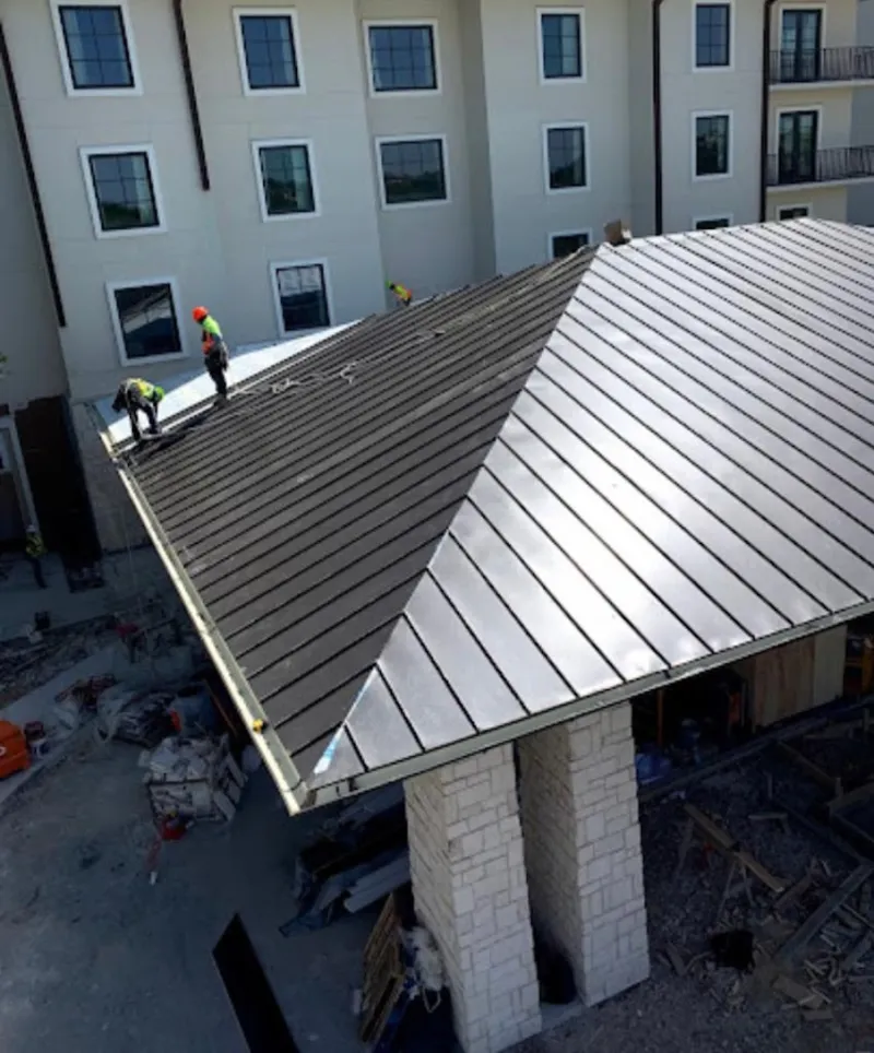 Crew installing standing seam metal roof panels on a commercial project in Erlanger